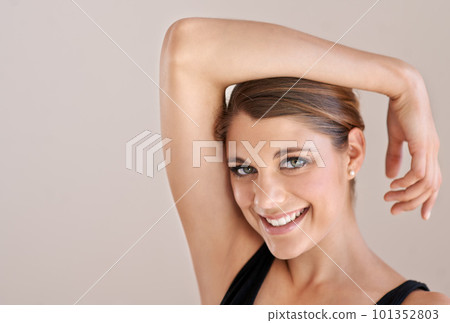 She has that certain something...Studio portrait of a young smiling woman with one arm resting on her head. 101352803