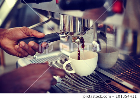 The perfect brew. Closeup shot of a male barista using an espresso machine to make a cup of coffee. The perfect brew. Closeup shot of a male barista using an espresso machine to make a cup of coffee. 101354411