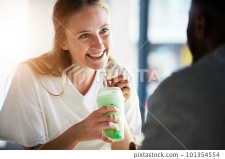 Woman, smile and smoothie on date in restaurant with man in interracial relationship, love and care. Girl, happy and drinking milkshake for health, nutrition or detox in conversation with black man 101354554