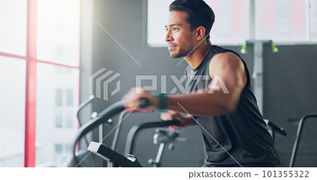Strong man, gym air bike and cardio training for exercise, workout and strong body, muscle and power in fitness club. Happy, healthy and young bodybuilder cycling fast on stationary bicycle machine Strong man, gym air bike and cardio training for exercise, workout and strong body, muscle and power in fitness club. Happy, healthy and young bodybuilder cycling fast on stationary bicycle machine 101355322