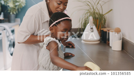 Little girl helping her mother with household chores at home. Happy mom and daughter wearing gloves while spraying and scrubbing the kitchen counter together. Kid learning to be responsible by doing Little girl helping her mother with household chores at home. Happy mom and daughter wearing gloves while spraying and scrubbing the kitchen counter together. Kid learning to be responsible by doing 101356585