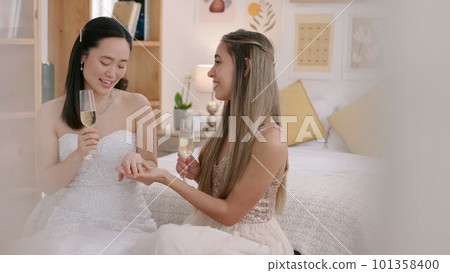 Bride drink champagne in bedroom, show ring and get motivation from friend before wedding. Maid of honor, give young Asian woman talk of love, support and hug before her marriage ceremony Bride drink champagne in bedroom, show ring and get motivation from friend before wedding. Maid of honor, give young Asian woman talk of love, support and hug before her marriage ceremony 101358400