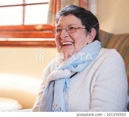 Happy elderly woman laughing sitting on sofa at home enjoying retirement Happy elderly woman laughing sitting on sofa at home enjoying retirement 101358503