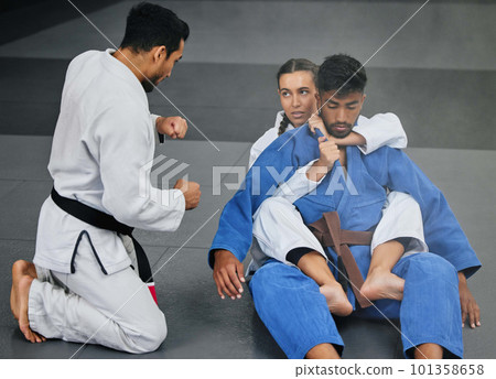 Karate training with trainer at a fitness studio, learning defense moves and practising fighting for competition together at a gym. Serious, active and fit woman doing routine judo workout at club Karate training with trainer at a fitness studio, learning defense moves and practising fighting for competition together at a gym. Serious, active and fit woman doing routine judo workout at club 101358658