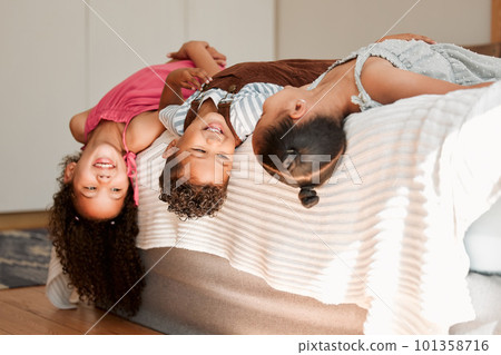 Kids lying on bed playful, fun and silly generation with cute hairstyle and smiling portrait. Relaxing, playing indoors showing growth, child development and childhood innocence from little siblings. 101358716