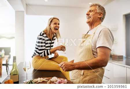 Happy and carefree couple cooking dinner laughing and enjoying the weekend in the kitchen at home. A mature husband relaxing and preparing a meal or lunch for his wife while having fun 101359361