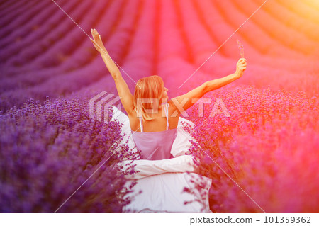 A middle-aged woman sits in a lavender field and enjoys aromatherapy. Aromatherapy concept, lavender oil, photo session in lavender 101359362