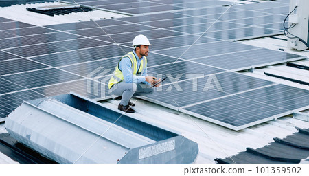 Engineer or contractor measuring solar panels on a roof of a building. Engineering technician or electrician installing alternative clean energy equipment and holding a tablet to record measurements 101359502