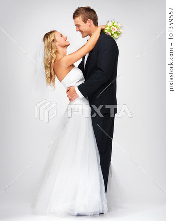 Happy couple hug after wedding against a studio mockup background with a smile and bouquet. Romantic young man and woman dancing with fashion, elegant and fancy suit and dress after marriage event 101359552