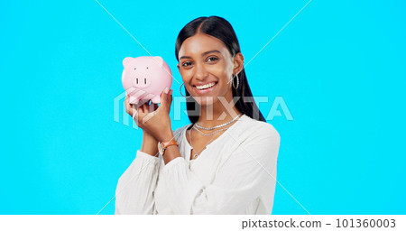 Piggy bank, happy face and Indian woman with a smile from savings, investment and finance. Isolated, blue background and portrait of a young female with happiness from cash saving and safe budget 101360003
