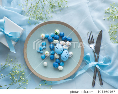 Festive Easter table setting with eggs, flowers and gift box on brown background Festive Easter table setting with eggs, flowers and gift box on brown background 101360567