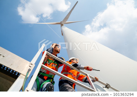 Two engineers or technician workers stand on base of big windmill or wind turbine Two engineers or technician workers stand on base of big windmill or wind turbine 101363294