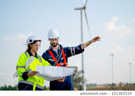 Caucasian engineer man and woman discuss together using drawing paper and stay in front windmill 101363524
