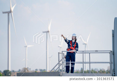 Engineer man or technician worker stand on base of windmill or wind turbine and point to left side 101363571