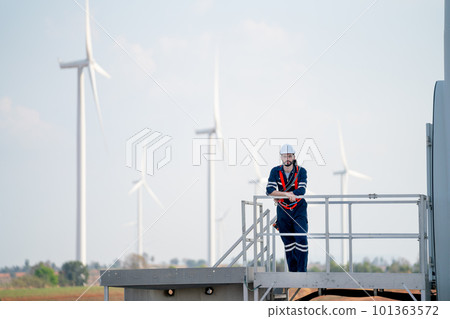 Engineer man or technician worker stand on base of windmill or wind turbine and look at camera 101363572