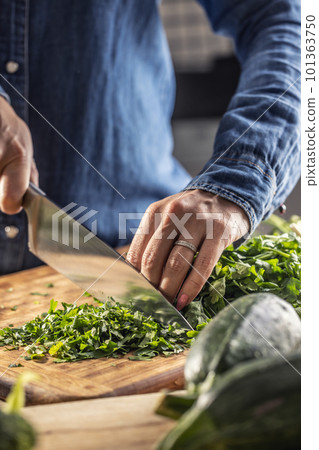 Seasonal greens use in the kitchen as woman chops parsley for freezing and later use in the winter Seasonal greens use in the kitchen as woman chops parsley for freezing and later use in the winter 101363750