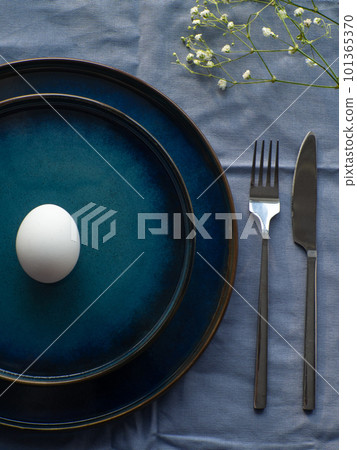 Festive Easter table setting with egg and flowers on blue background 101365370