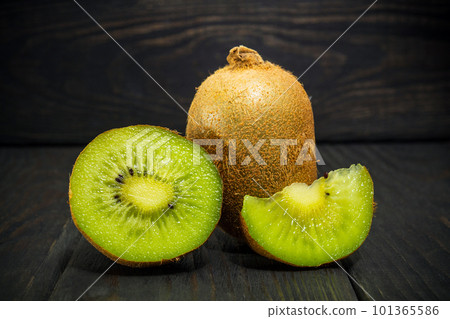 Whole kiwi fruit and his sliced segment on black vintage table. Idea for diet Whole kiwi fruit and his sliced segment on black vintage table. Idea for diet 101365586