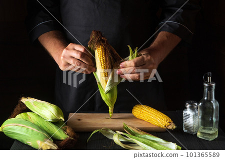 The chef peels ripe corn from the shell before cooking. Working environment in the restaurant kitchen. The hands of the cook close-up while working 101365589