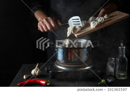 The chef cooks meat dumplings in a saucepan in the restaurant kitchen. Close-up of the hands of the cook during work. Free advertising space The chef cooks meat dumplings in a saucepan in the restaurant kitchen. Close-up of the hands of the cook during work. Free advertising space 101365597