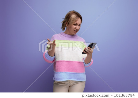 blond girl makes a purchase on the Internet holding a smartphone in her hands on a purple background 101365794