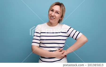 attractive blond young woman in green silk shirt laughing on blue background 101365813