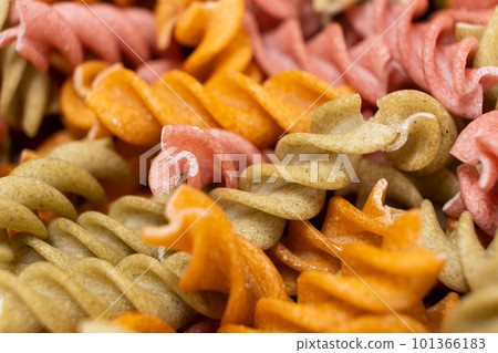 Rice vegetable pasta in the form of spirals, top view. Healthy rice pasta with tomatoes, celery, carrots and beets Rice vegetable pasta in the form of spirals, top view. Healthy rice pasta with tomatoes, celery, carrots and beets 101366183
