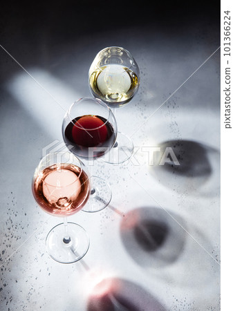 Pink rose,red and white wine glasses on light background with shadows. Pink rose,red and white wine glasses on light background with shadows. 101366224
