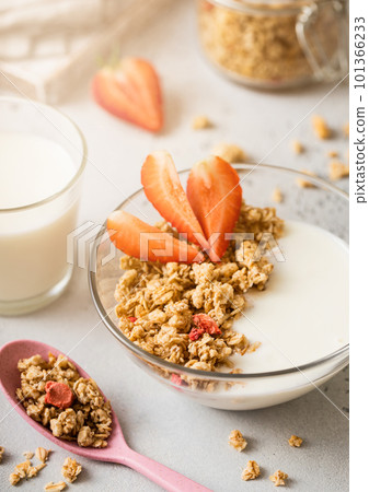 Homemade fresh granola with spoon and glass of milk with morning sun light 101366233