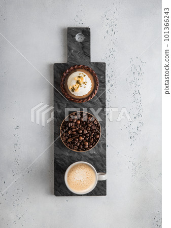 Black marble board with chocolate caramel tartalette and cup of coffee. 101366243