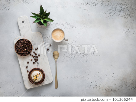 Coffee cup with raw beans and golden spoon and caramel dessert on marble board. 101366244