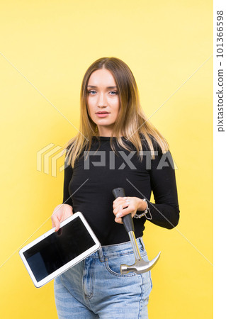 Woman with tablet and hammer, Studio lighting yellow background isolated, copy space Woman with tablet and hammer, Studio lighting yellow background isolated, copy space 101366598