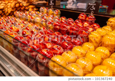 Close up of plastic cup filled with chopped healthy fruit and vegetables in grocery shop. Eco friendly, organic and healthy snack. Food in shelf in supermarket. Close up of plastic cup filled with chopped healthy fruit and vegetables in grocery shop. Eco friendly, organic and healthy snack. Food in shelf in supermarket. 101367240