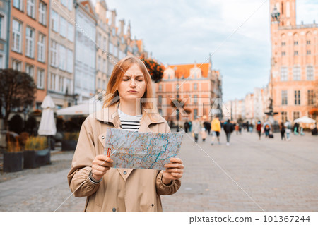 Lost young woman traveling with map in the central square in Gdansk old town. Traveling in Poland Lost young woman traveling with map in the central square in Gdansk old town. Traveling in Poland 101367244