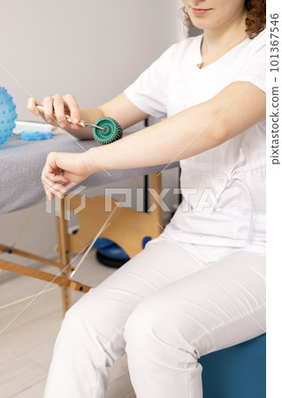 Rehabilitation Specialist, Physical Therapist Demonstrates Rehab Tool Meso Roller With Titanium Needles On Hand, Massage Ball With Pimples in Therapeutic Room. Healthcare, Rehabilitation. Vertical Rehabilitation Specialist, Physical Therapist Demonstrates Rehab Tool Meso Roller With Titanium Needles On Hand, Massage Ball With Pimples in Therapeutic Room. Healthcare, Rehabilitation. Vertical 101367546