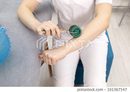 Rehabilitation Specialist, Physical Therapist Demonstrates Rehab Tool Meso Roller With Titanium Needles On Hand, Massage Ball With Pimples in Therapeutic Room. Healthcare, Rehabilitation. Horizontal Rehabilitation Specialist, Physical Therapist Demonstrates Rehab Tool Meso Roller With Titanium Needles On Hand, Massage Ball With Pimples in Therapeutic Room. Healthcare, Rehabilitation. Horizontal 101367547