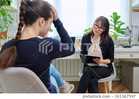 Teenage girl high school student talking with mentor, psychologist in office 101367597