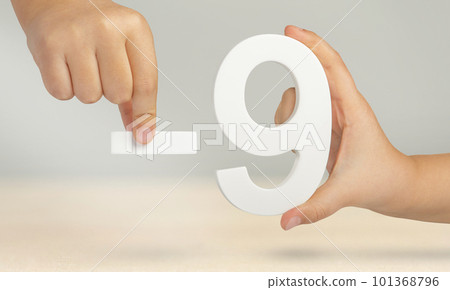 Minus nine. The number nine and the minus symbol in a hand close-up on a light gray background. The concept of removal or taking away. 101368796
