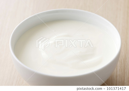 Plain yogurt served in a white bowl 101371417