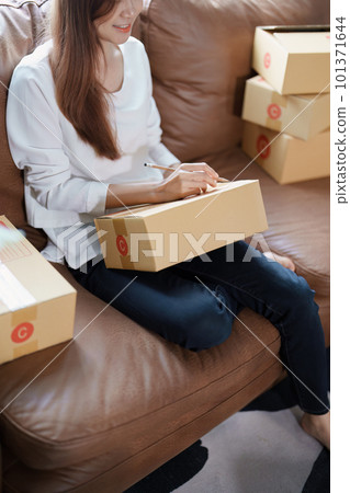Starting small business entrepreneur of independent Asian female online seller packing products to send to customers and SME delivery concept. Starting small business entrepreneur of independent Asian female online seller packing products to send to customers and SME delivery concept. 101371644