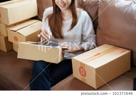Starting small business entrepreneur of independent young Asian woman online seller is using tablet computer and taking orders to pack products for delivery to customers. SME delivery concept. Starting small business entrepreneur of independent young Asian woman online seller is using tablet computer and taking orders to pack products for delivery to customers. SME delivery concept. 101371646