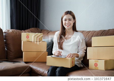Starting small business entrepreneur of independent young Asian woman online seller is using tablet computer and taking orders to pack products for delivery to customers. SME delivery concept. Starting small business entrepreneur of independent young Asian woman online seller is using tablet computer and taking orders to pack products for delivery to customers. SME delivery concept. 101371647