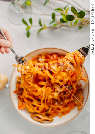 Italian pasta, tomato sauce. Two female hands in the frame, girls eat pasta, hold forks in their hands, top view, Italian cuisine. Italian pasta, tomato sauce. Two female hands in the frame, girls eat pasta, hold forks in their hands, top view, Italian cuisine. 101371658