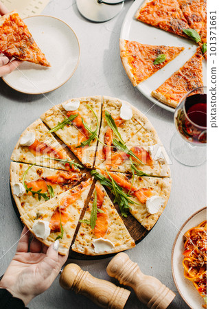 Traditional Italian pizza, vegetables, ingredients on a light background.Top view. a piece of pizza in the hand.Festive table. company of friends 101371661