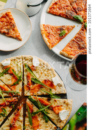 Traditional Italian pizza, vegetables, ingredients on a light background.Top view. a piece of pizza in the hand.Festive table. company of friends Traditional Italian pizza, vegetables, ingredients on a light background.Top view. a piece of pizza in the hand.Festive table. company of friends 101371664