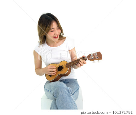 Young asian woman in white t-shirt and jean playing an Ukulele guitar. Portrait on white background with studio light. 101371791