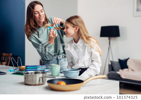 Mother braids her daughter's braids before school at breakfast Mother braids her daughter's braids before school at breakfast 101374325