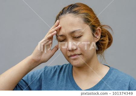 Asian women touch their temples right side, feel a headache or dizzy, feeling tired. grey background Asian women touch their temples right side, feel a headache or dizzy, feeling tired. grey background 101374349