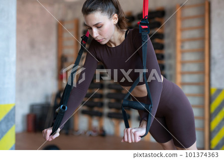 Fit woman doing push-up exercise with trx 101374363