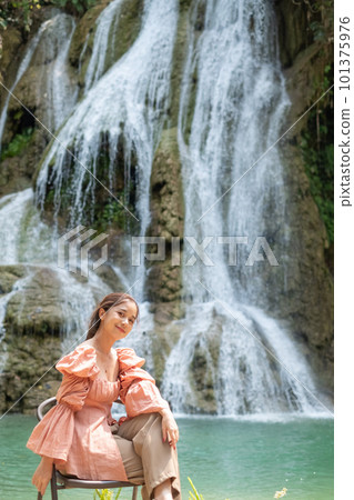 Young Asian woman sitting on a chair In front of the Khoun Moung Keo Waterfall 101375976
